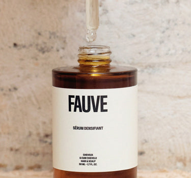 Présentant du flacon du Sérum Densifiant avec sa pipette intégrée